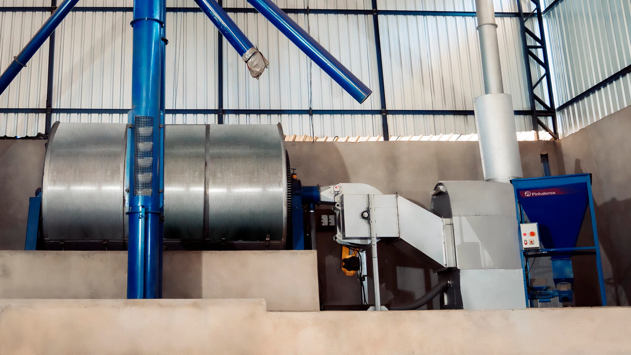 Secador de Cafe Completo Pinhalense , montado em galpão, com fornalha e ventilador  alimentador de palha, e que utiliza fogo indireto para a secagem do café.